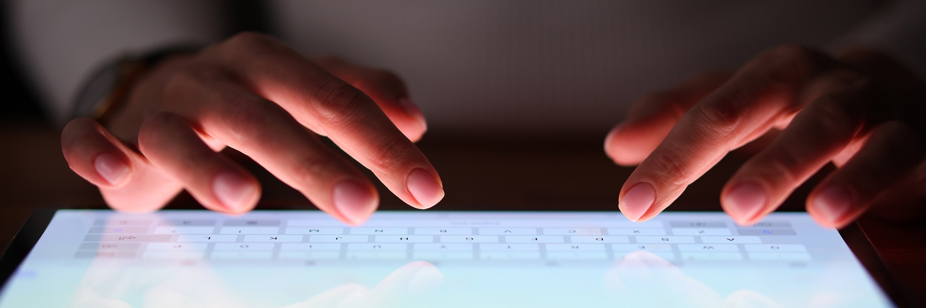 Female fingers are typing on tablet screen at night. People's dependence on modern gadgets concept